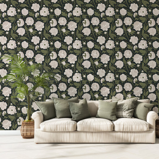 A living room with a cream sofa with green cushions scattered across it next to a large green plant, showing 'Celestial' which is a dark green botanical wallpaper featuring large white peony flowers, delicate green leaves and golden star details in a vintage-inspired repeating floral pattern.