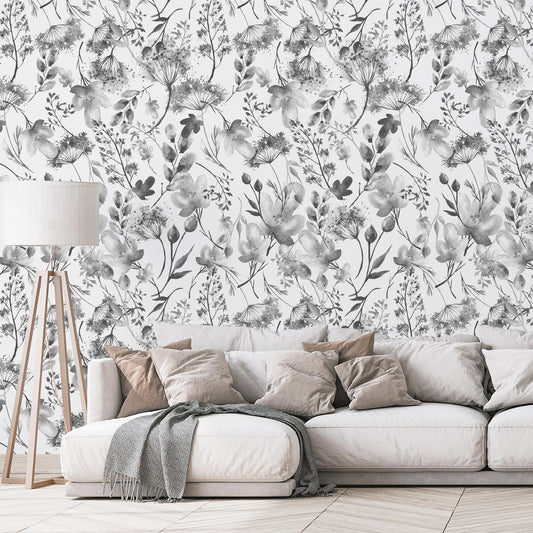 A living room with neutral furnishings showing 'Matilda' which is a grey and white wallpaper featuring delicate watercolor floral illustrations with soft botanical blooms and leaves in a repeating pattern.