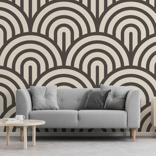 A living room showing a grey fabric sofa with a low coffee table featuring 'Jabrielle' which is a cream wallpaper featuring bold black retro arches in a repeating geometric pattern with a subtle textured effect.