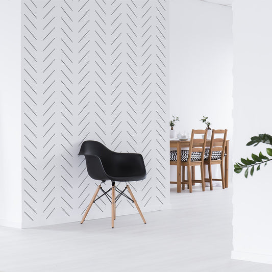 An open kitchen/living room diner with a feature wall showing the Livia wallpaper which is a monochrome wallpaper featuring a minimalist herringbone pattern made from thin diagonal lines arranged in a repeating geometric design.