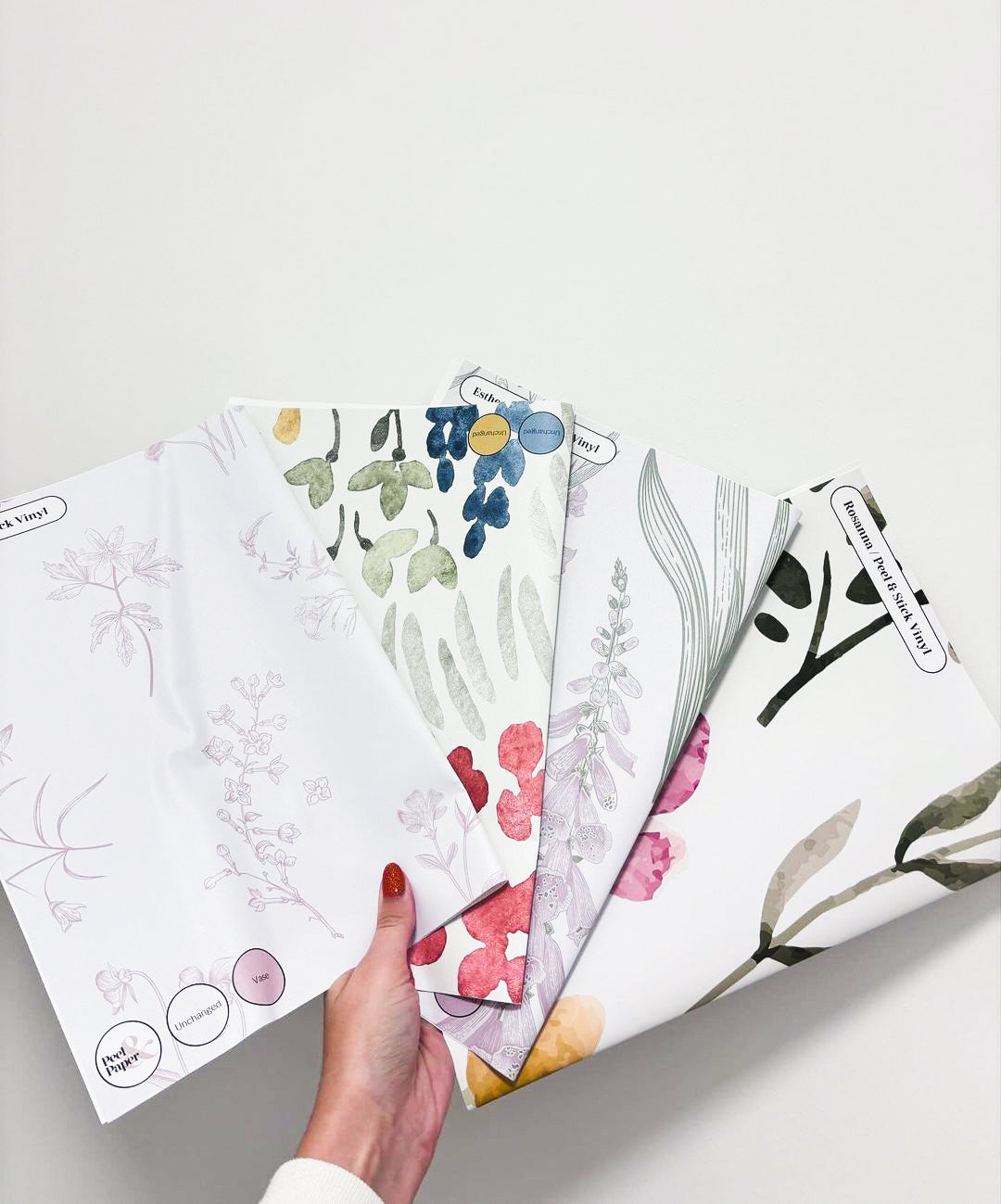 An Image of A Womans Hand Which is Holding Samples Of Peel & Paper's Floral Designs