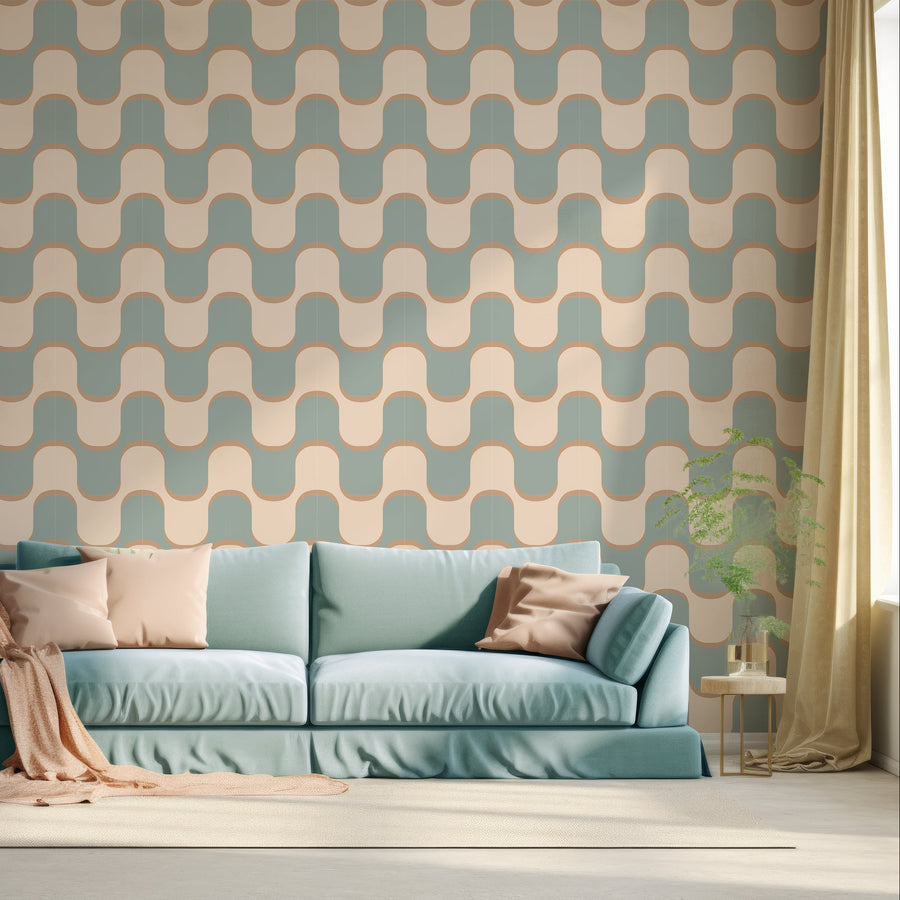 A living room with a dusty blue sofa scattered with cushions, shows 'Asmara' which is a royal blue wallpaper featuring flowing gold curved lines and geometric wave shapes in a retro-inspired repeating abstract pattern.