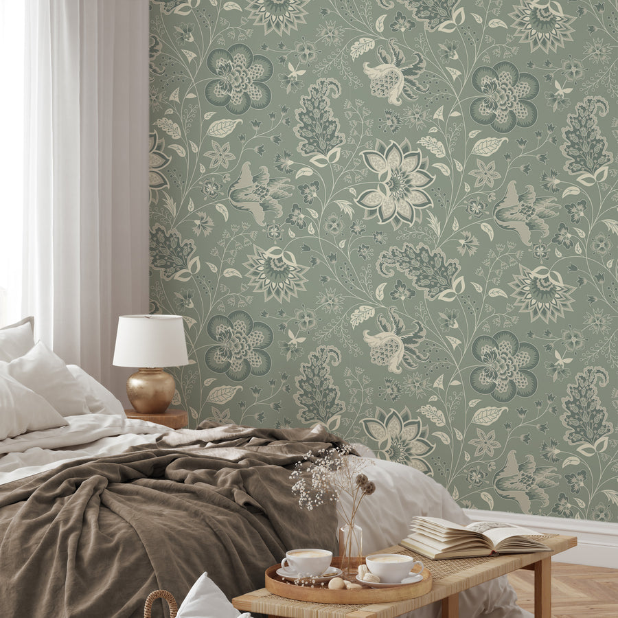A relaxed styled bedroom with the wallpaper Azalea which is sage green coloured featuring chinoiserie-style floral blooms, leafy vines and decorative botanical motifs in a repeating pattern.