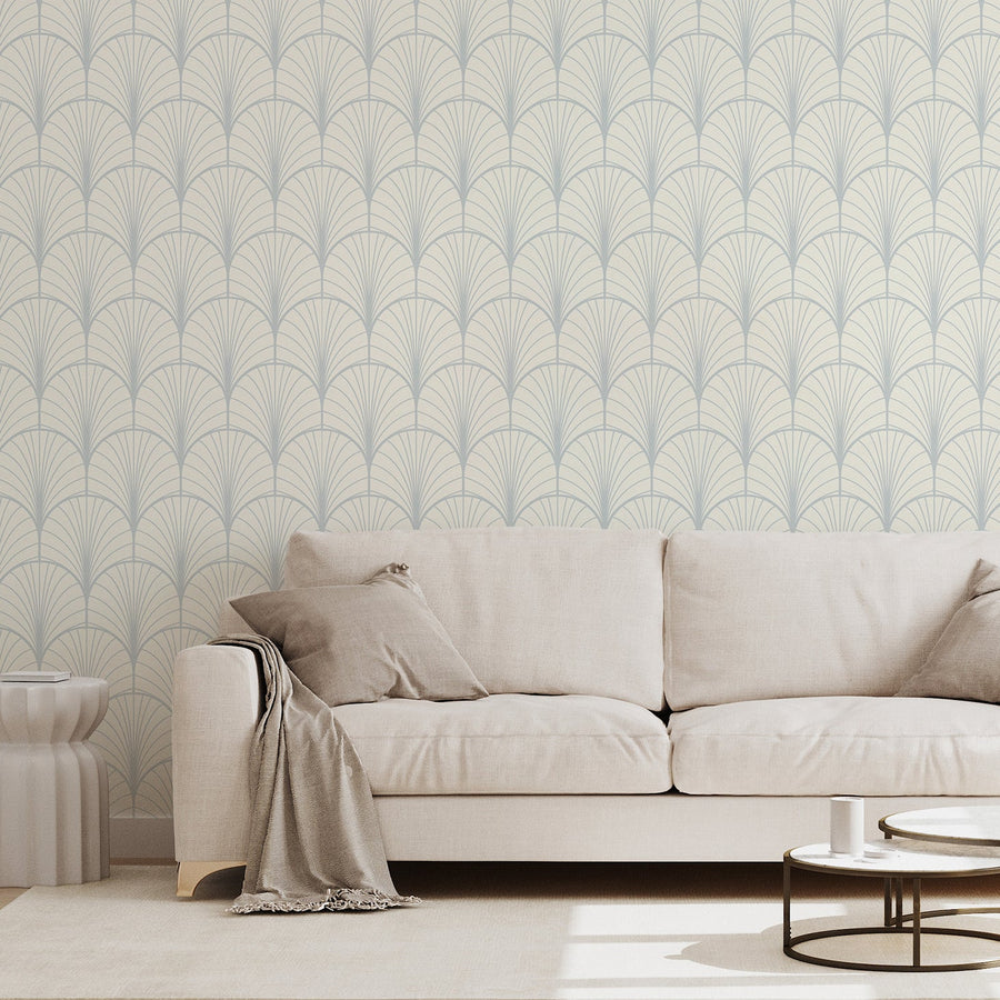 A living room with a beige fabric sofa featuring the Theodora wallpaper which is a Art Deco themed repeating geometric fan shapes in an elegant vintage-inspired pattern with a bold symmetrical design.