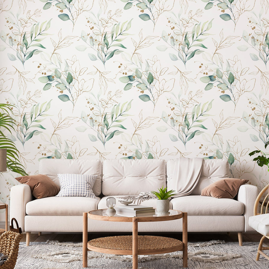 A living room with a cream sofa featuring the Eucalyptus wallpaper which is a green wallpaper featuring delicate eucalyptus leaves with gold-effect line illustrations in a soft botanical repeating pattern.